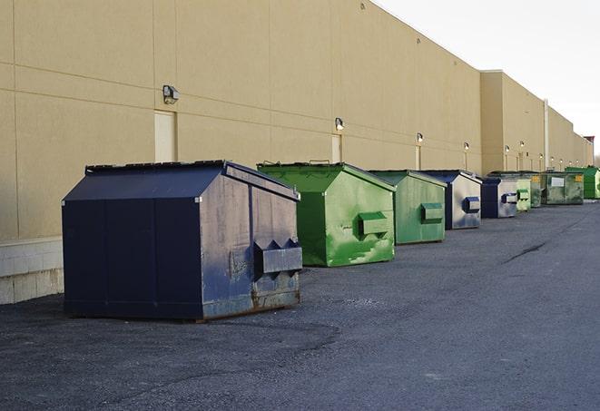 construction workers toss wood scraps into a dumpster in Adair